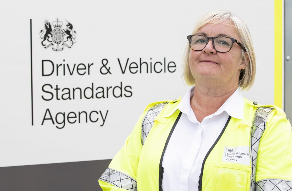 DVSA staff member standing in front of a white DVSA sign.