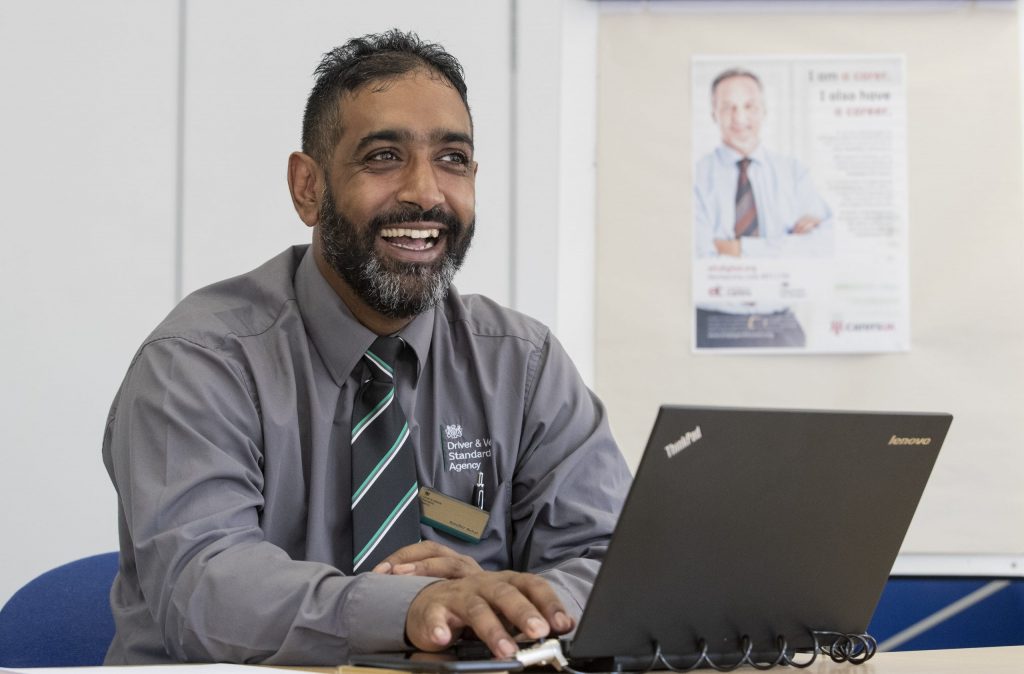 Male DVSA staff member sitting at desk with laptop