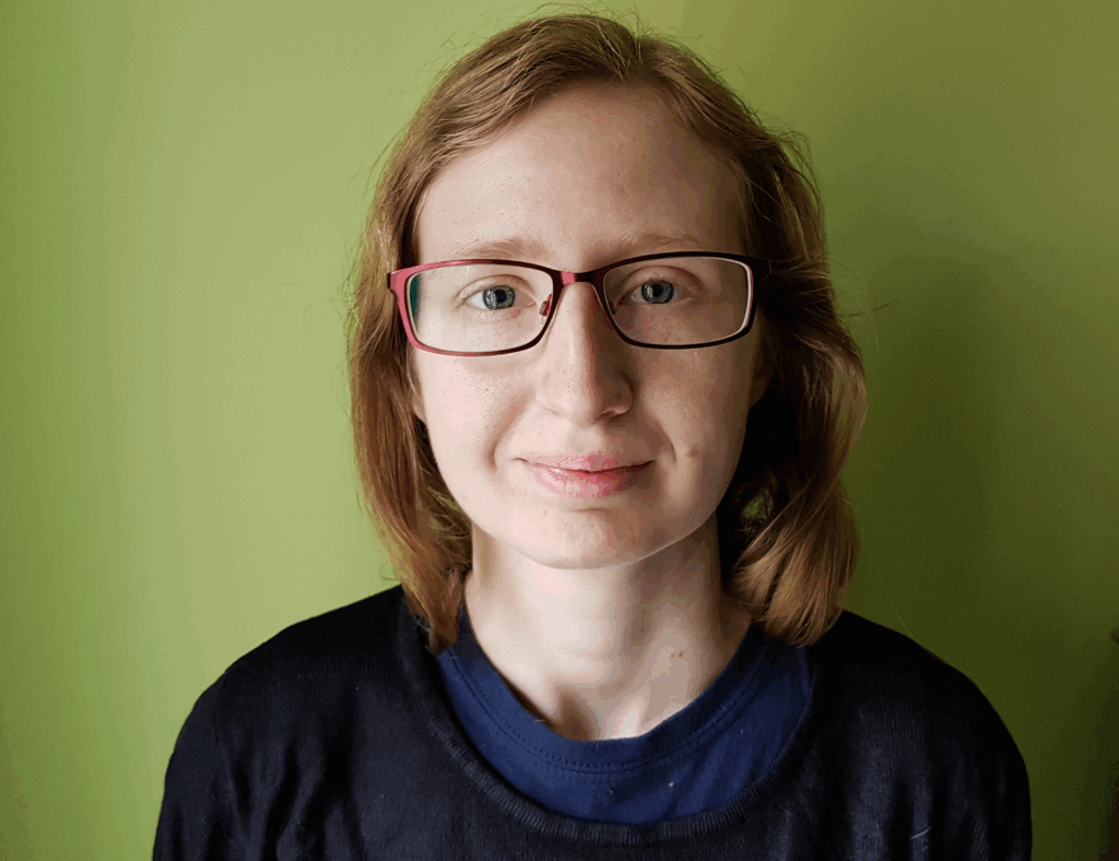 Picture of Katherine Hooper wearing a black jumper and glasses in front of a green background